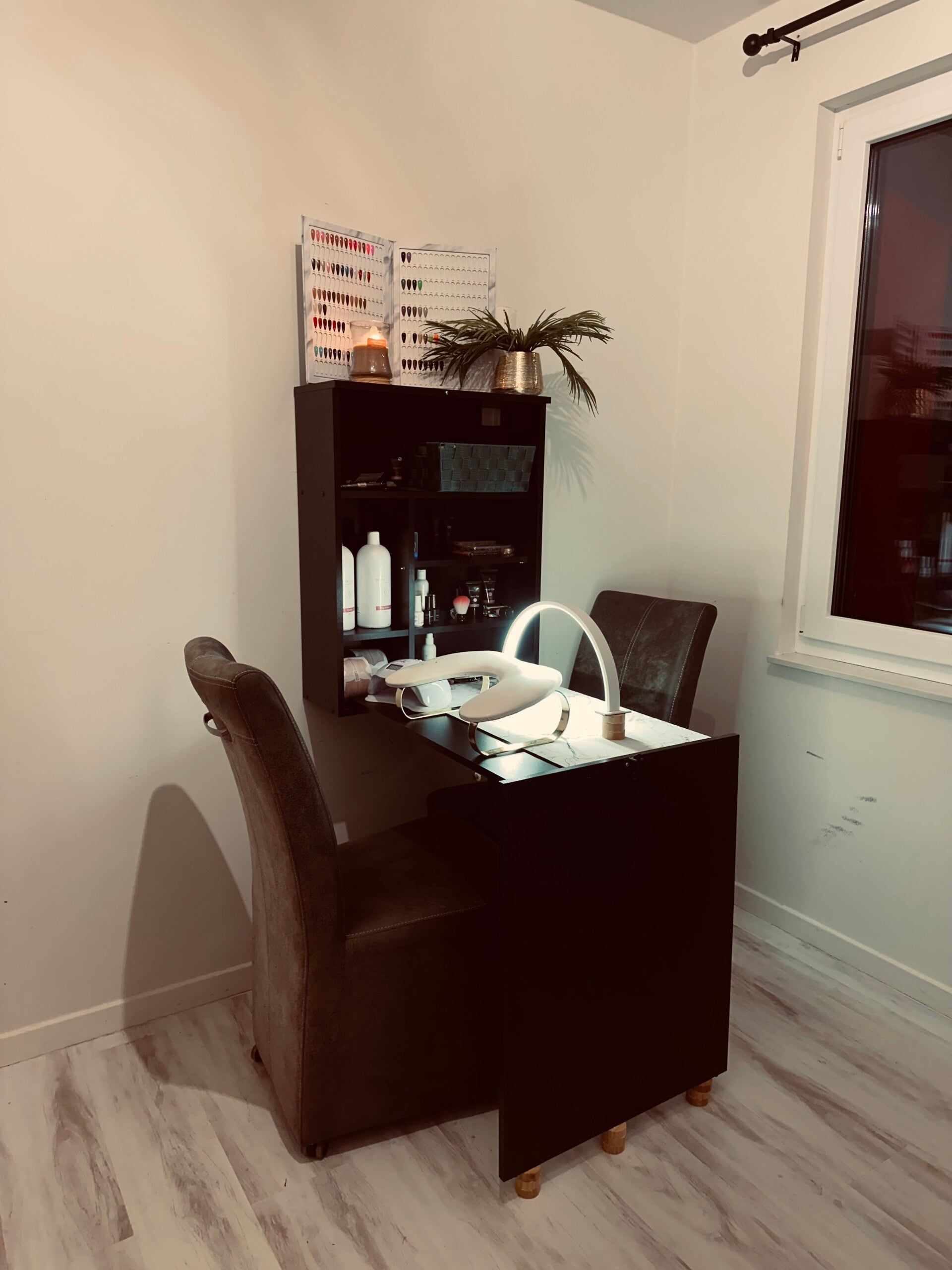 De behandelplek: een donkere nageltafel met lamp en een rek met kleurstalen
